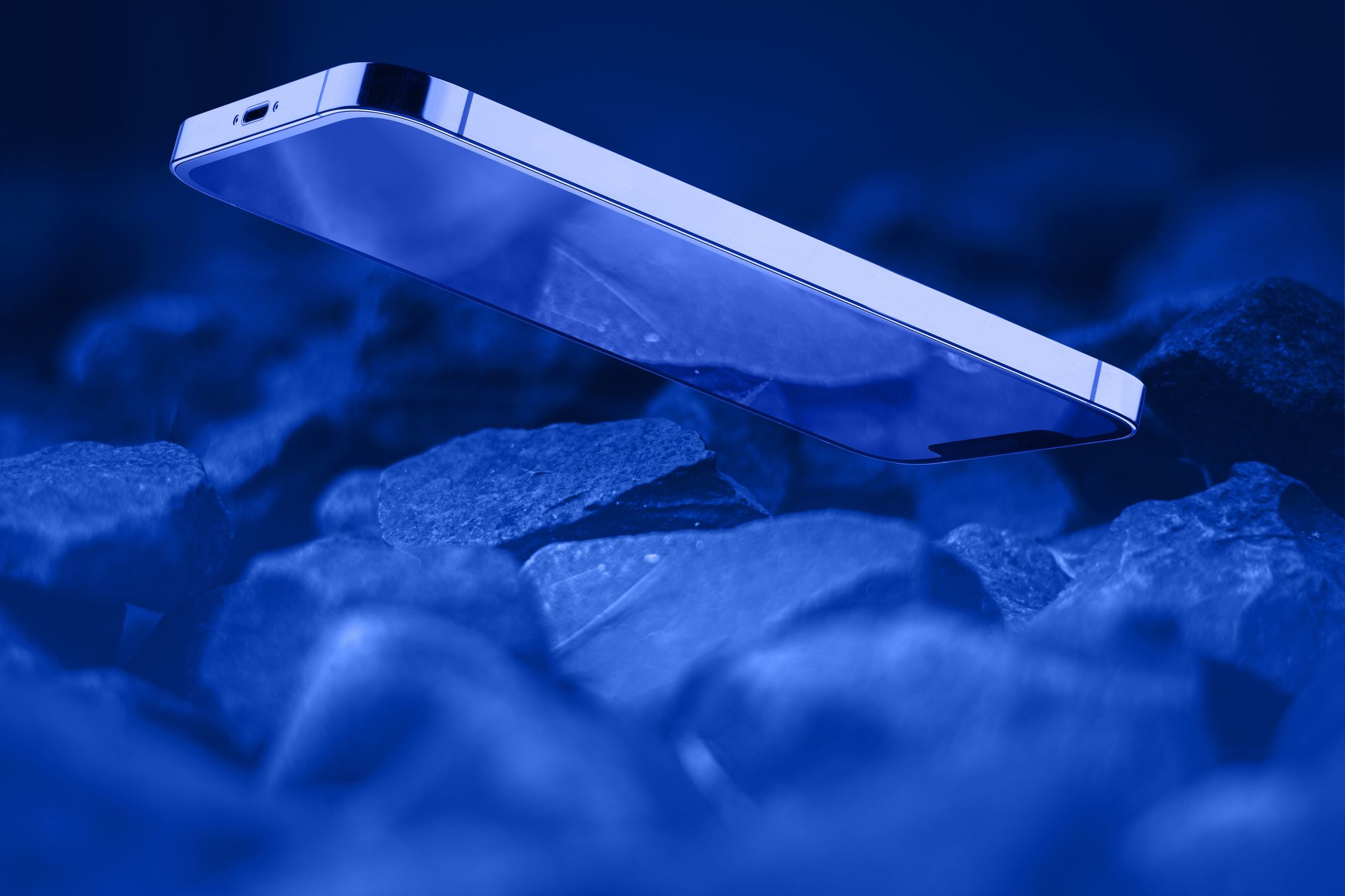 Cell phone with broken glass on gravel granite stones, unbreakable gadget